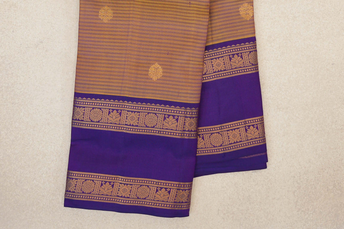 Folded light weight Kanchipuram silk saree with mustard yellow and deep purple stripes, small gold-toned motifs and wide floral-patterned purple borders.